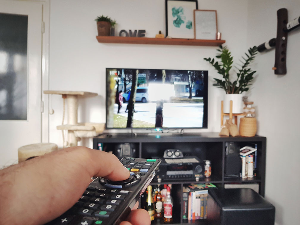 Mann hält Fernbedienung in der Hand und schaut TV