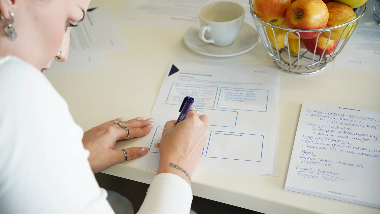 Teilnehmerin skizziert im Video-Konzeptions-Workshop Ideen auf einem Content Board, daneben handschriftliche Notizen zu Szenen